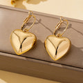 Un par de pendientes de moda para mujer en forma de corazón liso, oro - plata