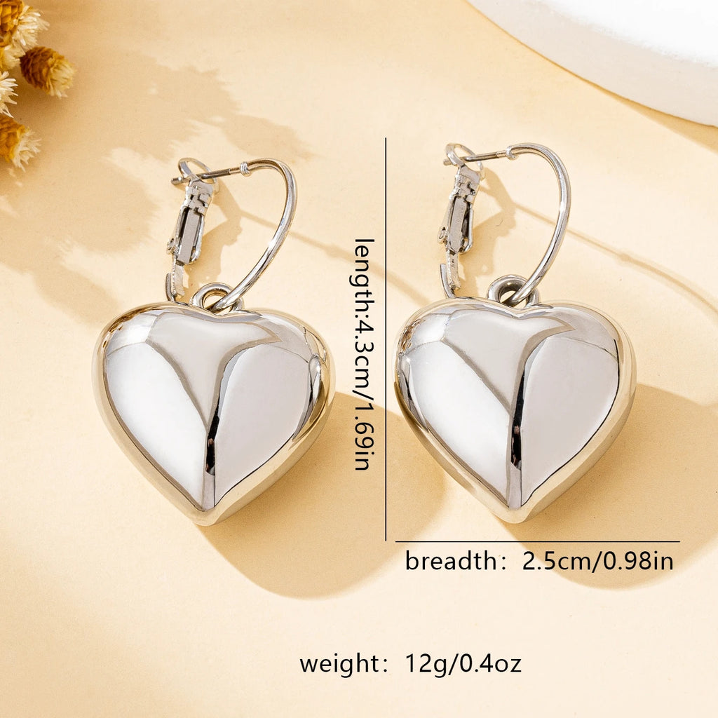 Un par de pendientes de moda para mujer en forma de corazón liso, oro - plata